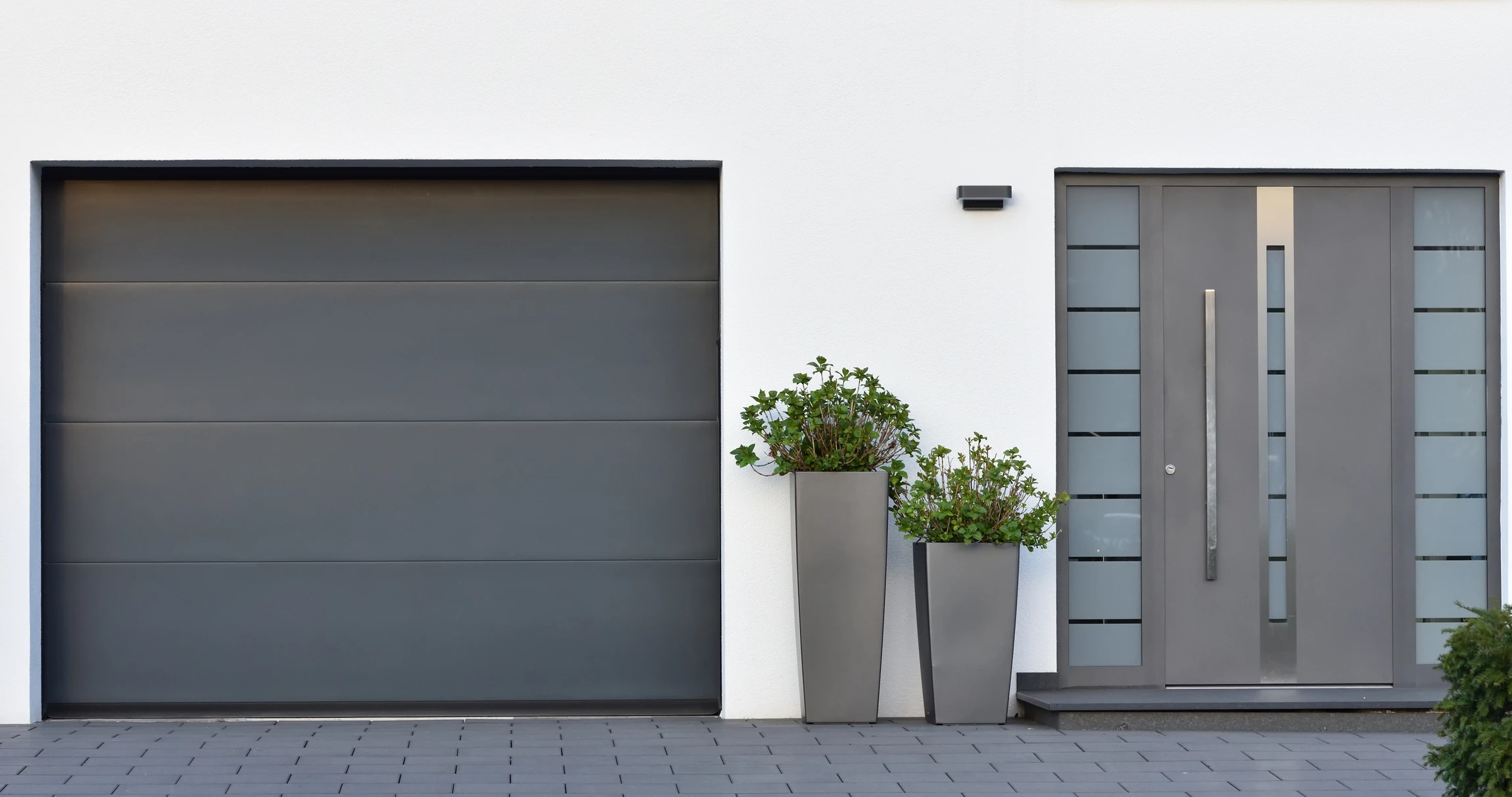 Façade résidentielle moderne avec porte d'entrée contemporaine et porte de garage sectionnelle
